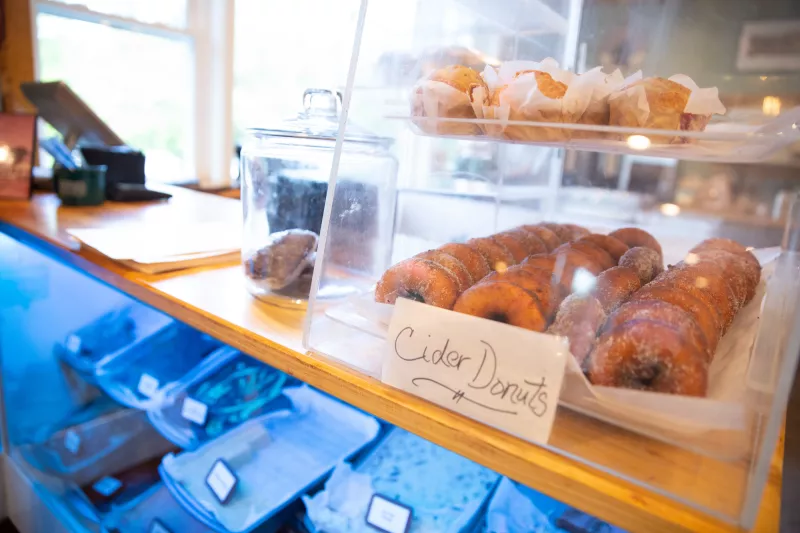 A countertop display case holds freshly baked cinnamon sugar donuts.