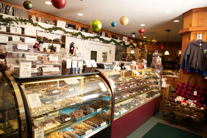 A chocolate shop features a glass display case and Christmas decor.