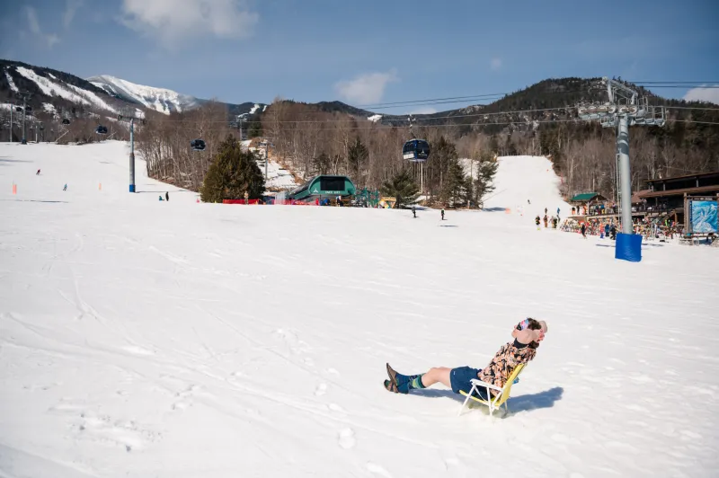 A person sits on the mountain in a lawn chair in shorts.