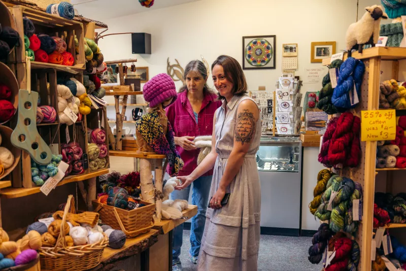 Two women browse an art gallery and fiber arts shop.