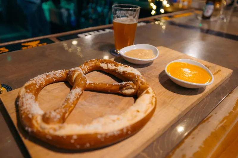 A pretzel and dips on a wooden board