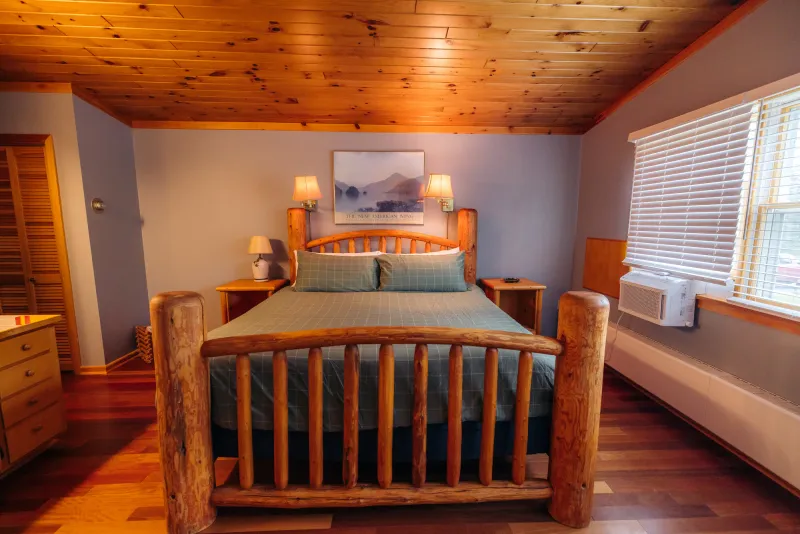 A fluffy mattress atop an Adirondack-style log bed frame in a guest room at New Vida Preserve