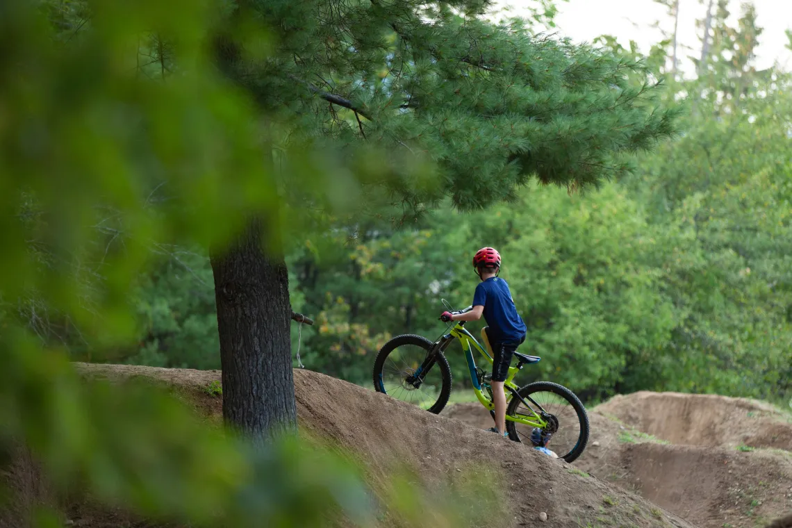A child on a mountain bike looks at dirt jumps at the Wilmington Bike Park