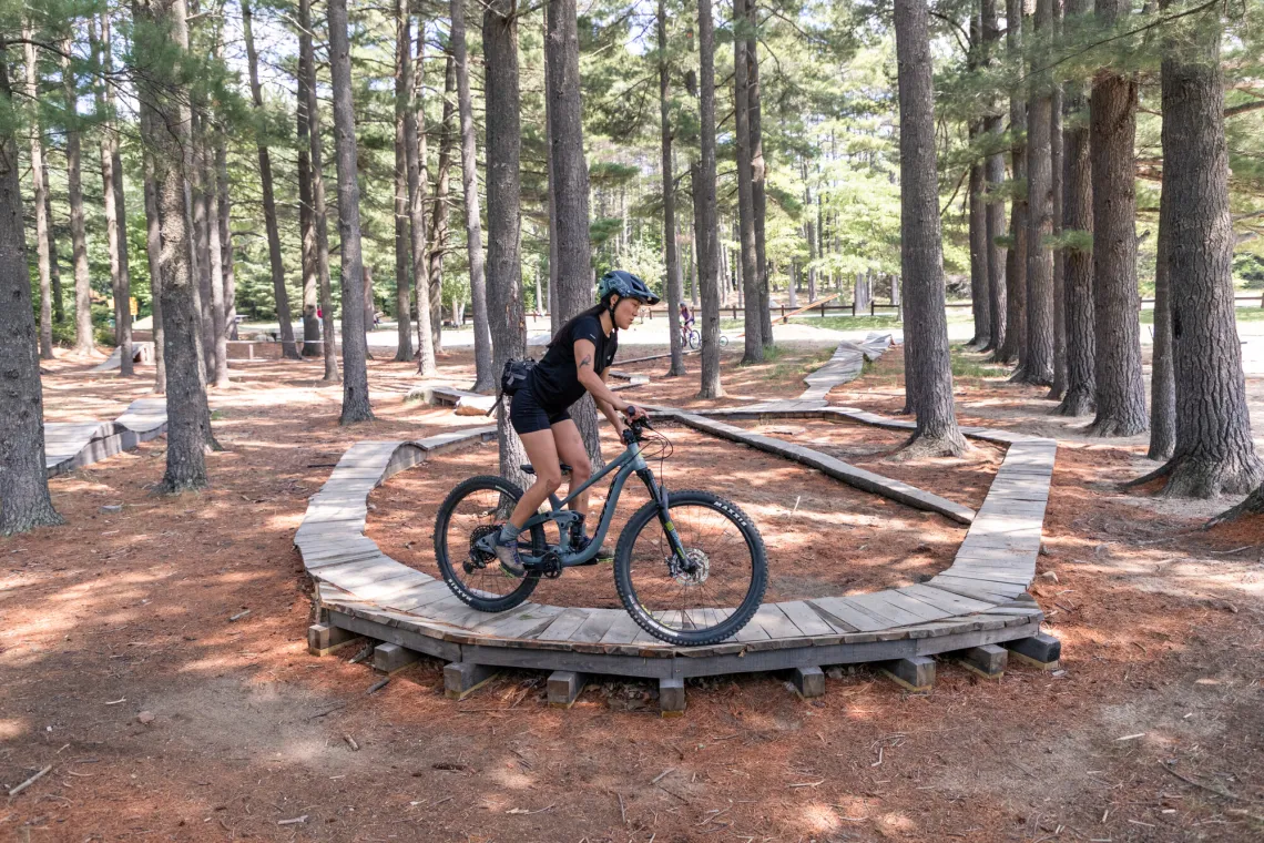 A woman on a mountain bike on a raised wooden platform at the mountain bike skills park in Wilmington, NY