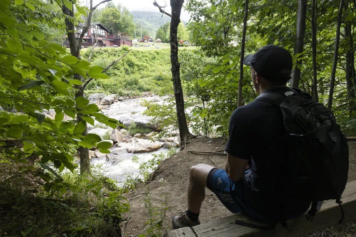 A person sits and overlooks the Flume behind the Hungry Trout Resort