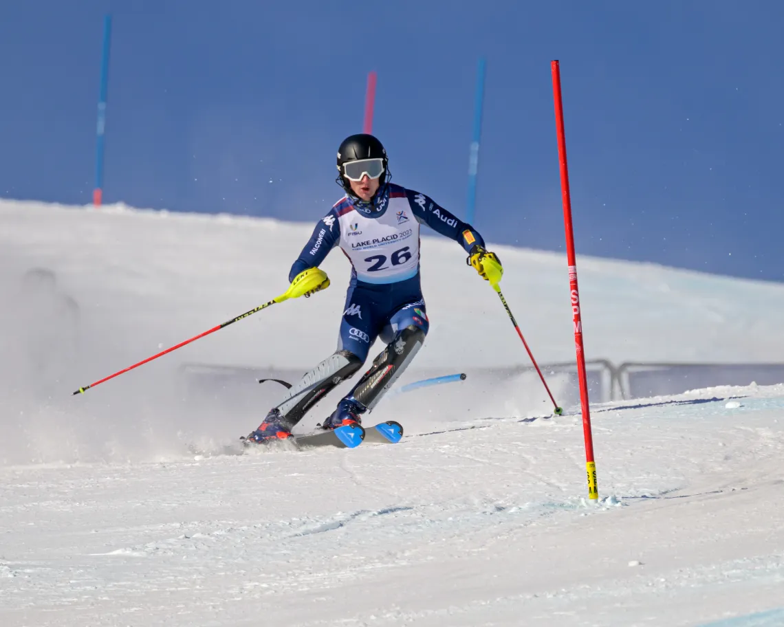 A male slalom skier races down a slalom course on a snowy mountain