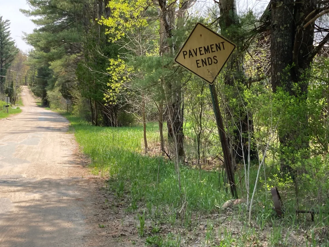A gravel road with "pavement ends" sign on the side.