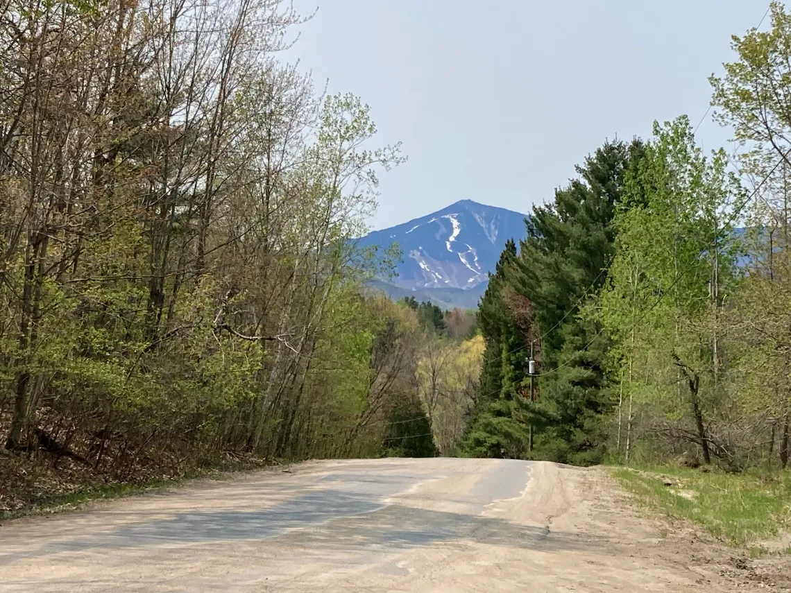 A gravel road leading to a mountain.