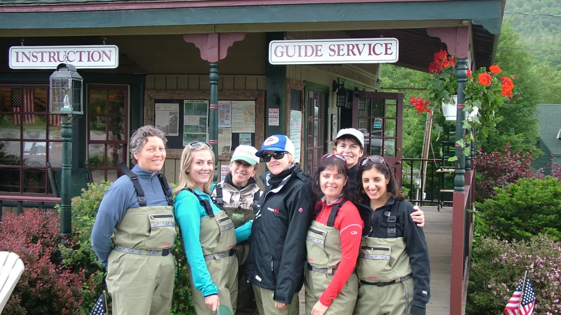 A group of women in fishing gear pose as a group in front of a fishing shop.